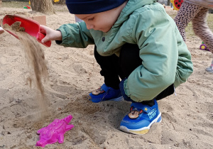 Chłopiec przesypuje piasek