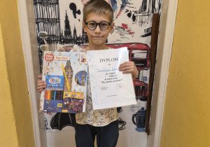 Staś stoi z nagrodą i dyplomem