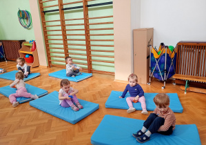 Maluszki przekładają woreczki pod nogami w pozycji siedzącej