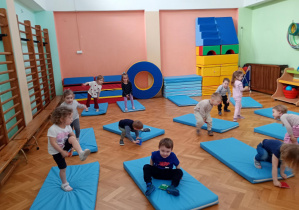 Maluszki przekładają woreczki pod nogami w pozycji stojącej