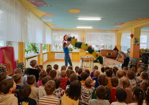 Prowadzące wyciągają z worka wielką pluszową stonogę