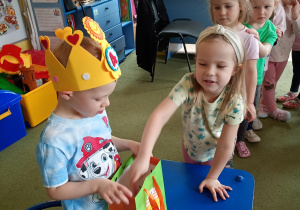 Dziewczynka częstuje się urodzinowym cukierkiem od kolegi