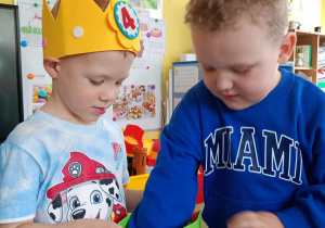 Chłopiec częstuje się urodzinowym cukierkiem od kolegi