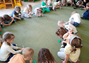 Dzieci próbują za pomocą wdechu podnieść liście na słomkach