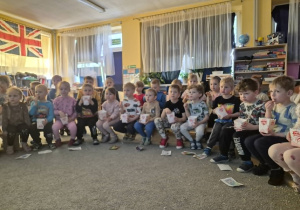 Dzieci oglądają bajkę jedząc popcorn