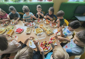 Dzieci nadziewają owoce na patyki