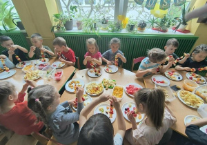 Dzieci nadziewają owoce na patyki