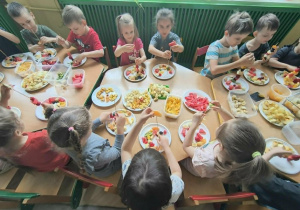 Dzieci nadziewają owoce na patyki