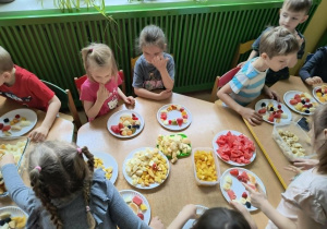 Dzieci jedzą pyszne szaszłyki owocowe