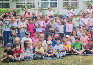 dzieci oglądają przedstawienie siedząc na kocu na trawie