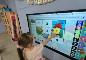 dziewczynka gra na tablicy multimedialnej