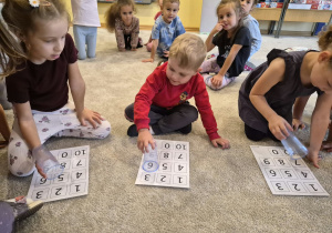 dzieci wskazują cyfry przezroczystymi kubkami