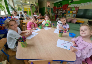Dzieci kolorują kolorowankę przy stoliku