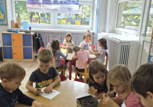 dzieci kolorują przy stolikach