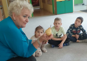 nauczyciel opowiada o owocach, w ręku trzyma gruszkę